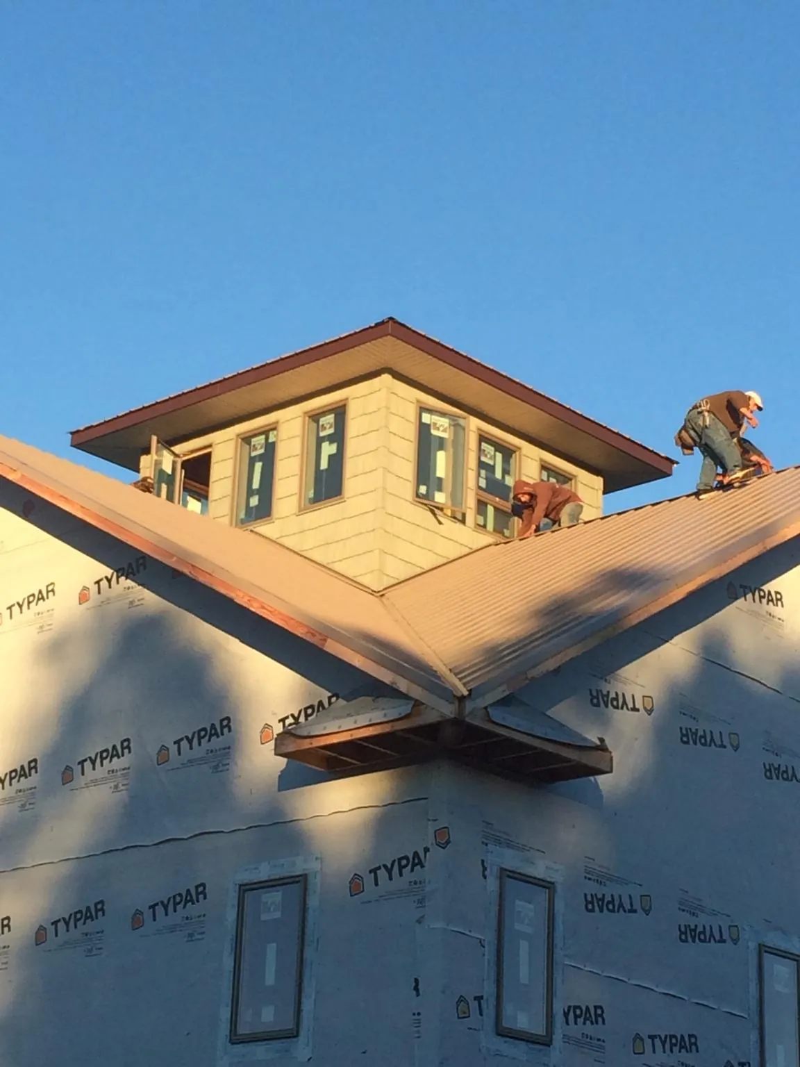 Roofers working around a rooftop cupola on a new metal roof at sunset — Roof Waterproofing in Chester by Roofing Brothers